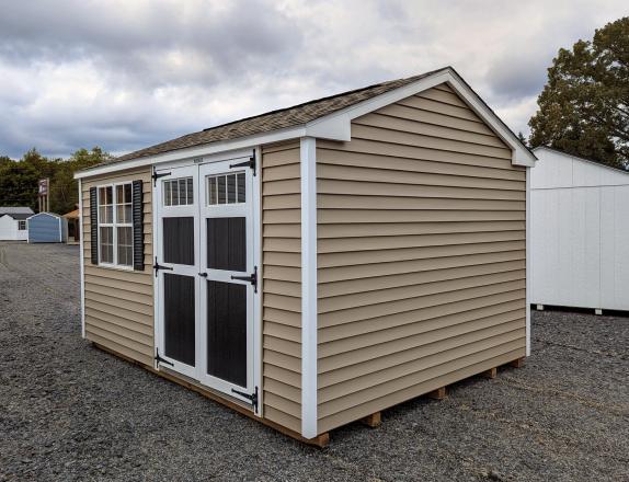 10x14 peak series shed in pebble clay straight lap vinyl siding with white trim and corners, black shutters and door, and weatherwood shingles.